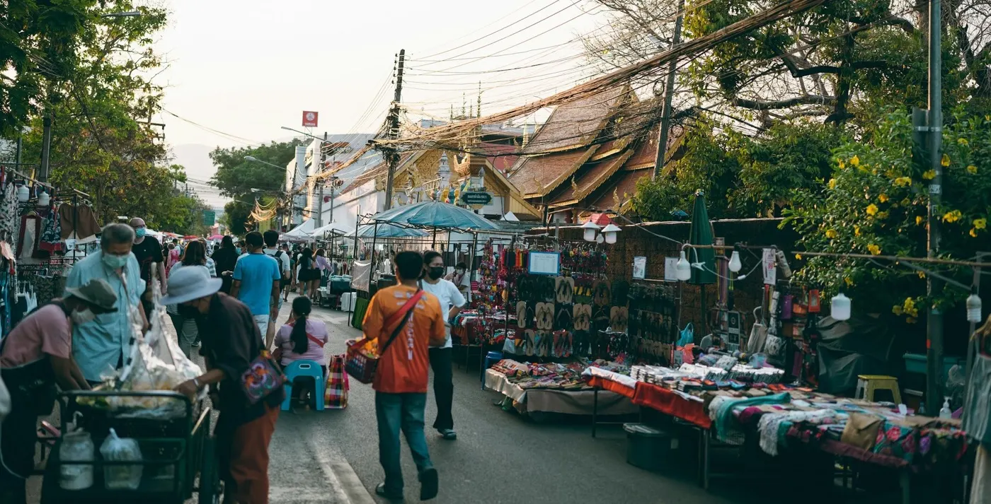 A walking-street market in Chiang Mai, temple roofs behind the stalls